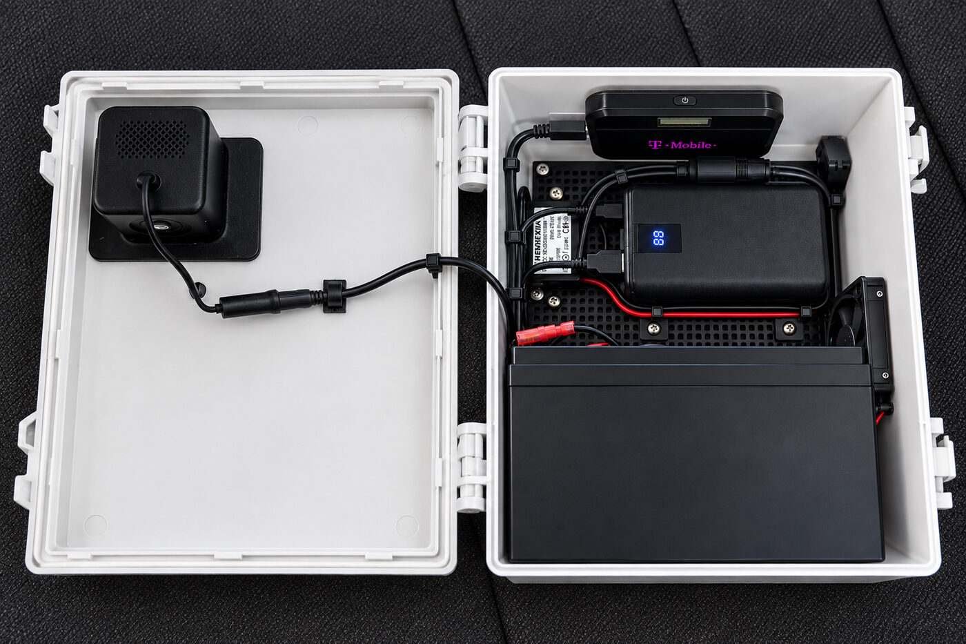 The enclosure open, showing the camera on the lid, the T-Mobile hotspot, power unit, cooling fan and battery